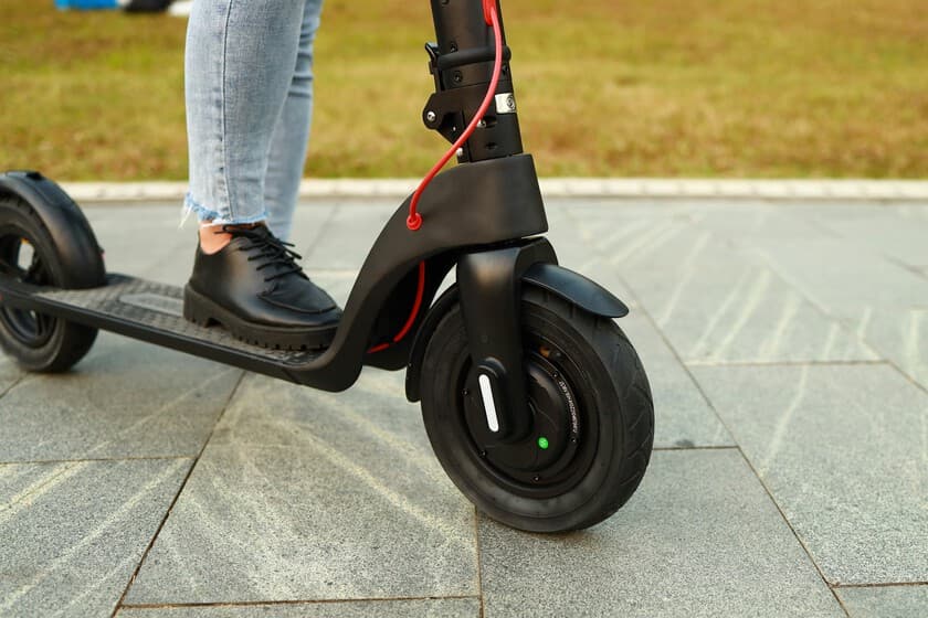 Patinete eléctrico modificado en una carretera urbana, con luces de policía al fondo.
