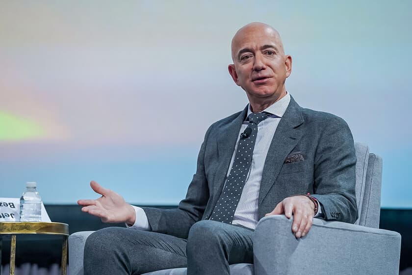 Jeff Bezos en una entrevista, con expresión seria, fondo de estudio de grabación