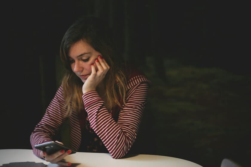 Una persona mirando su teléfono con una app de análisis facial, reflejando preocupación en su rostro.