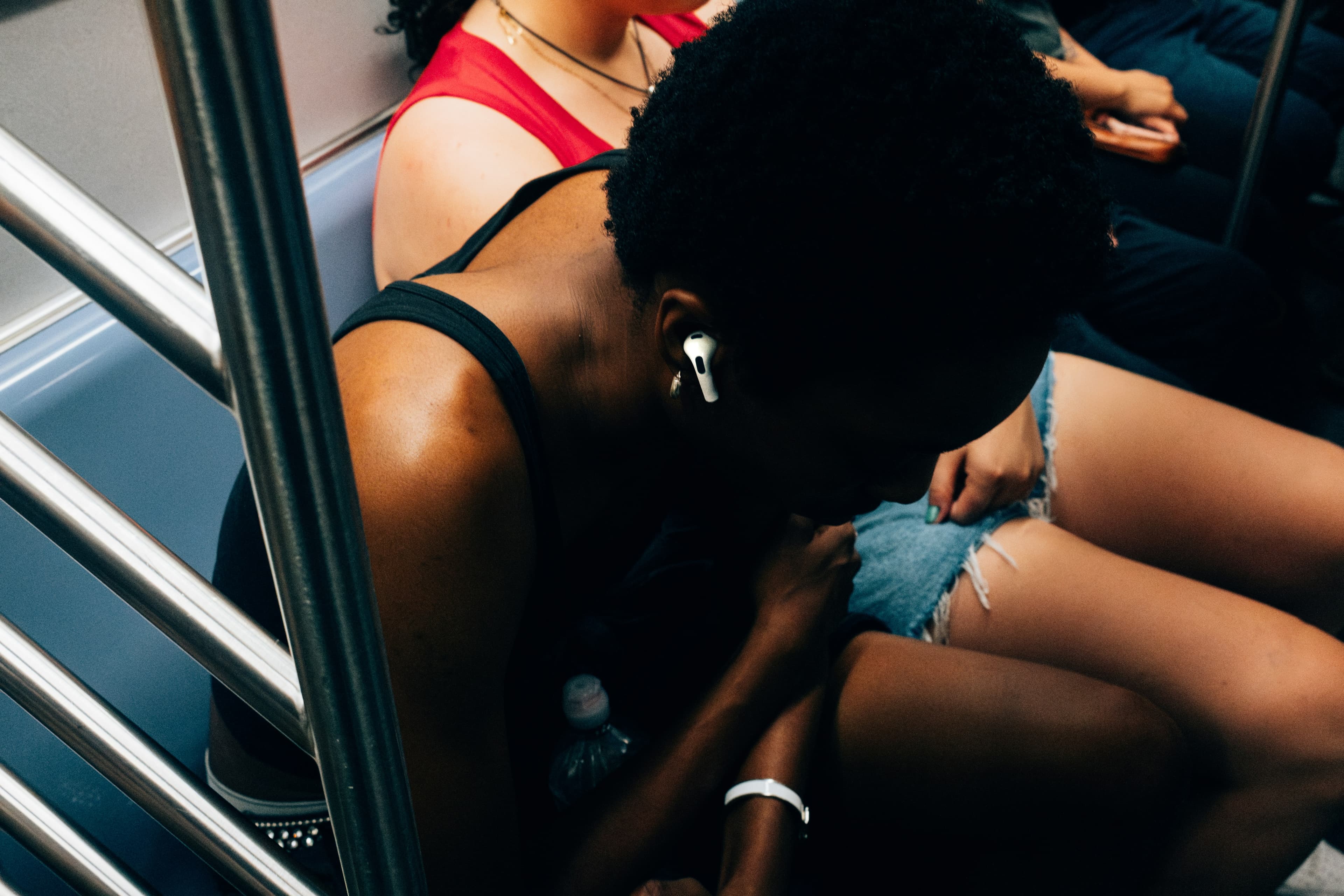 Persona con AirPods mirando el móvil en un espacio público, rodeada de gente pero aislada