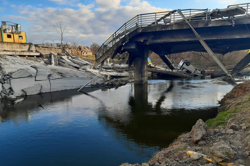 Dron ucraniano sobrevolando un puente dañado, con humo y escombros al fondo