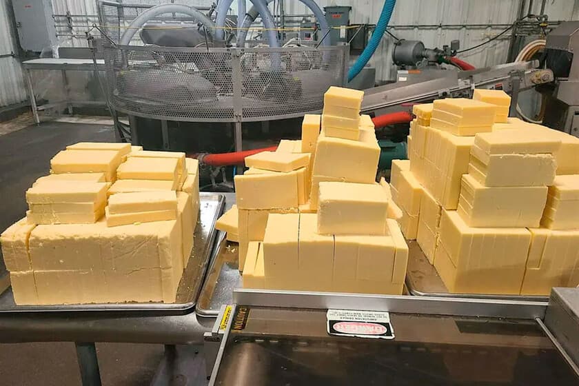 Queso artesanal en una tabla de madera con un teléfono móvil mostrando una interfaz de IA al lado
