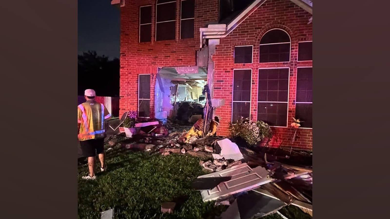 Coche Tesla accidentado contra una casa, con daños visibles en la fachada y el vehículo
