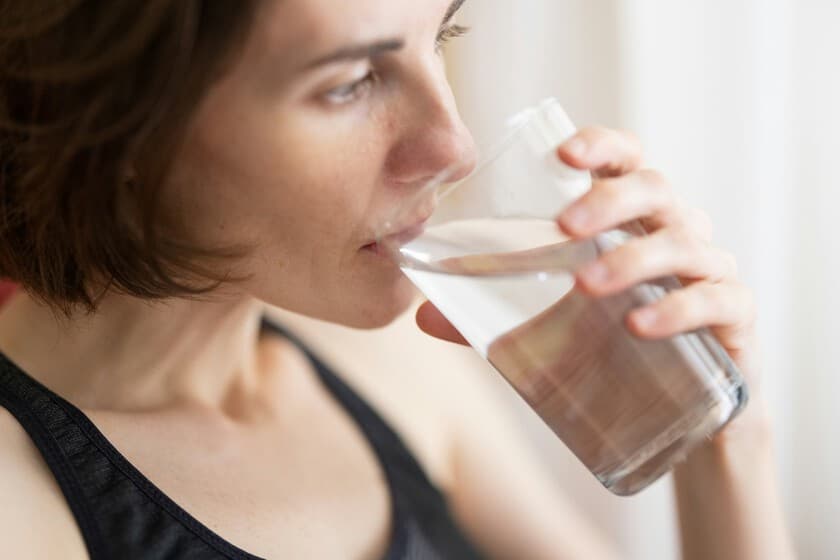 Vaso de agua junto a un despertador, simbolizando el mito del agua en ayunas para adelgazar