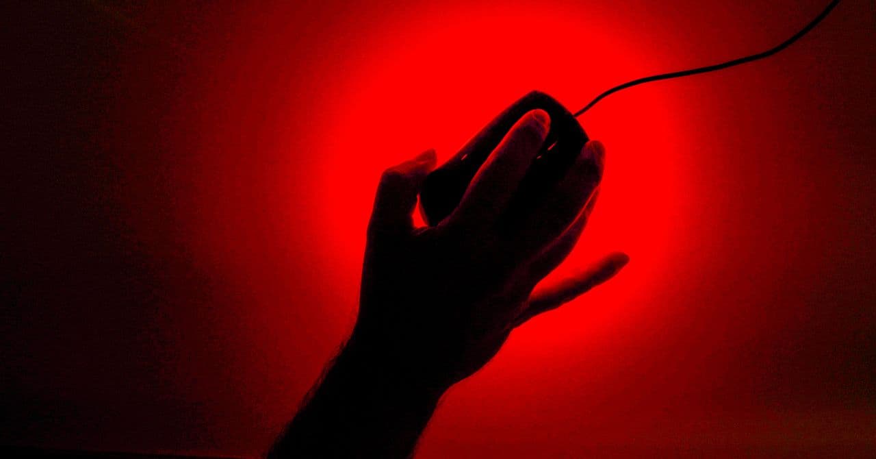 Persona escribiendo en un teclado con un ojo de vigilancia superpuesto