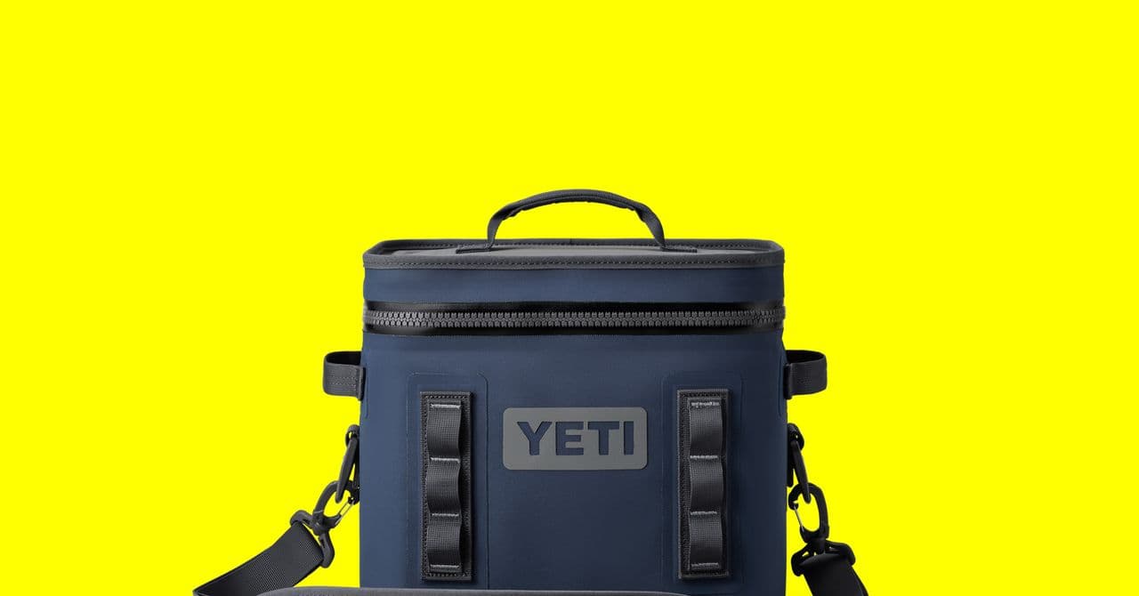 Nevera Yeti Tundra en exterior con hielo y latas, fondo de playa